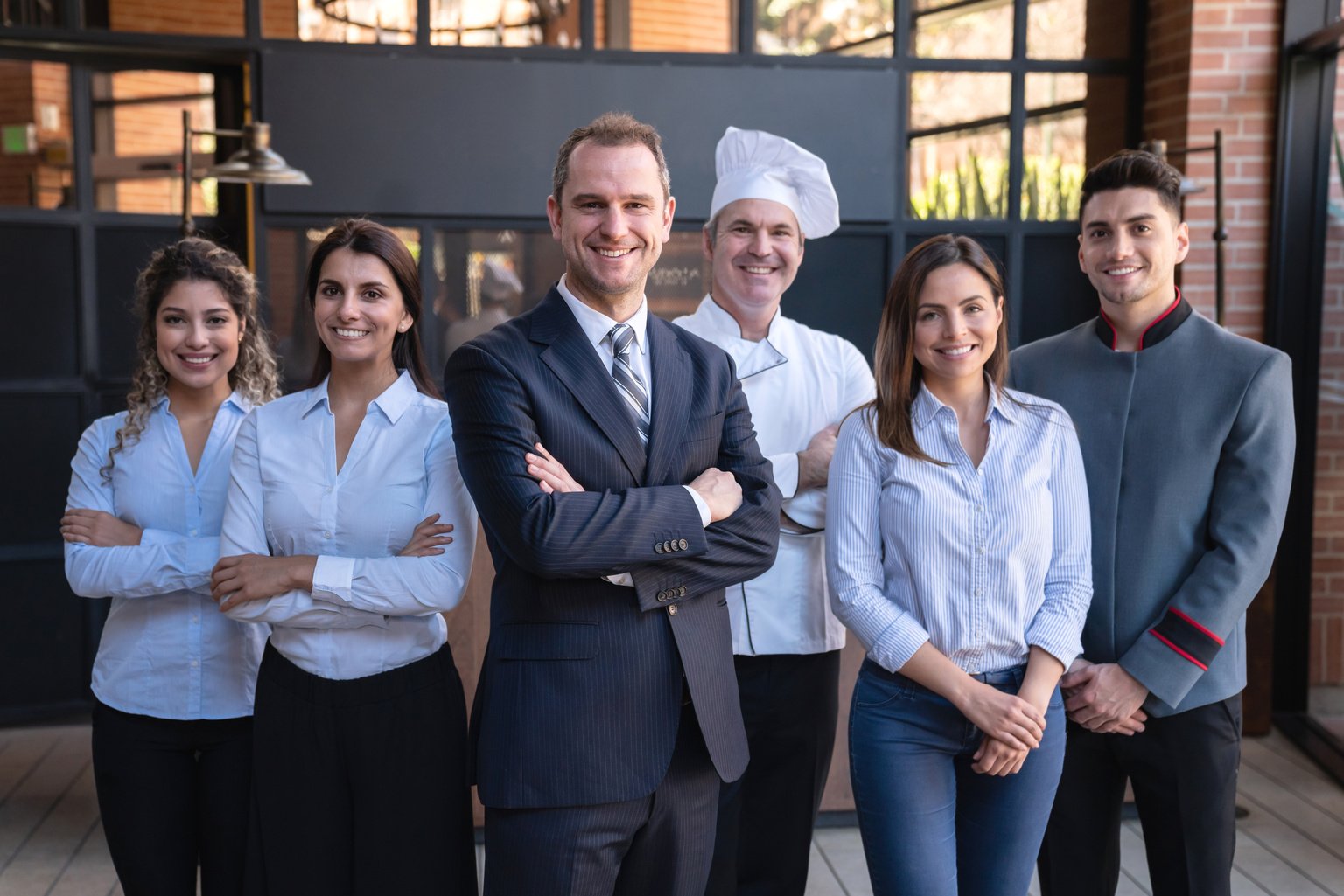 Cheerful latin american team of hotel staff all facing camera smiling